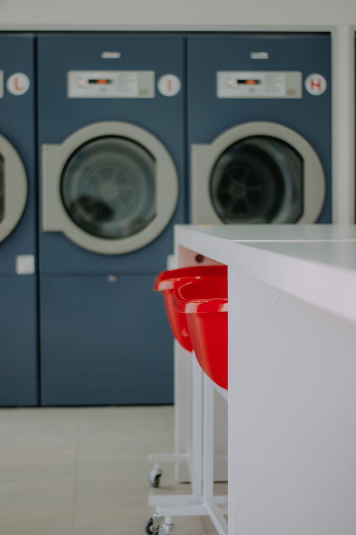 Conceptual photo of a tidy self-service laundromat: rows of blue washing machines and a folding table
